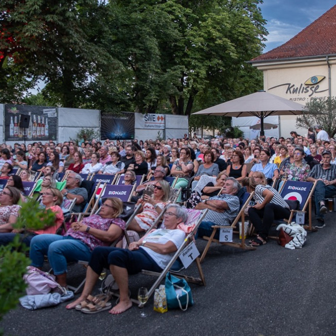 Menschen sitzen auf Klappstühlen und schauen einen Film.